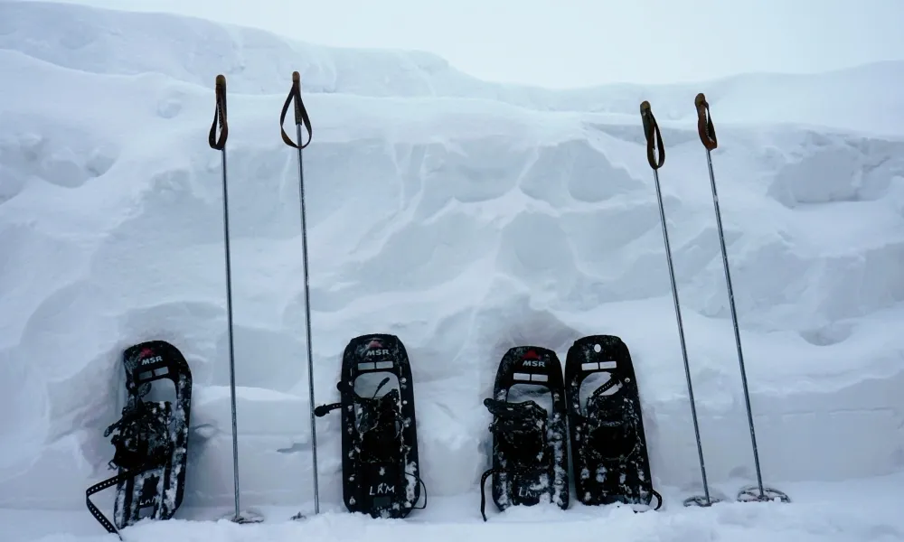 Två par snöskor som står lutade mot en snödriva