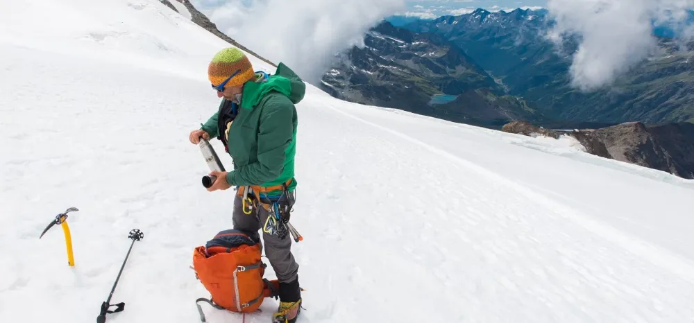 Man på en bergstopp med stegjärn under skorna